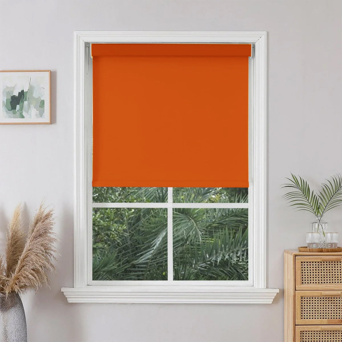 Red Joydeco custom blackout roller shade partially lowered in a white window, blocking sunlight.