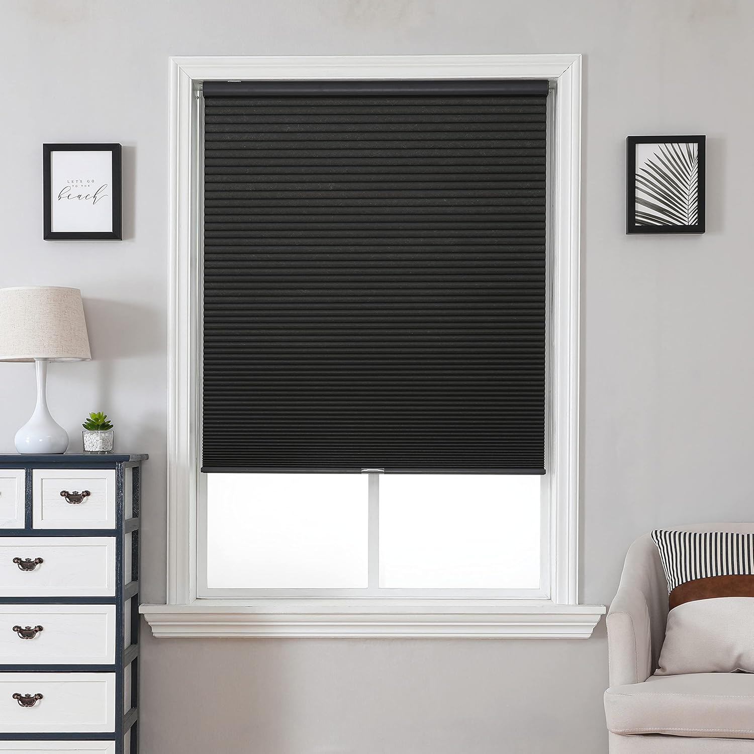 Black cordless cellular blackout shade with honeycomb texture, displayed in a modern living room setting.