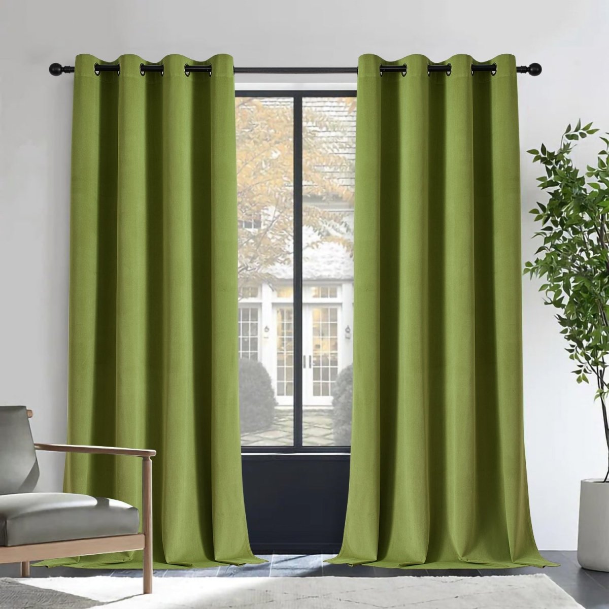 Joydeco moss green velvet blackout curtains, 2 panels with grommets, in a room with armchair and plant.