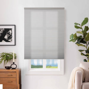 Joydeco custom light grey cordless blackout cellular shade in white window, honeycomb texture, with plant & artwork.