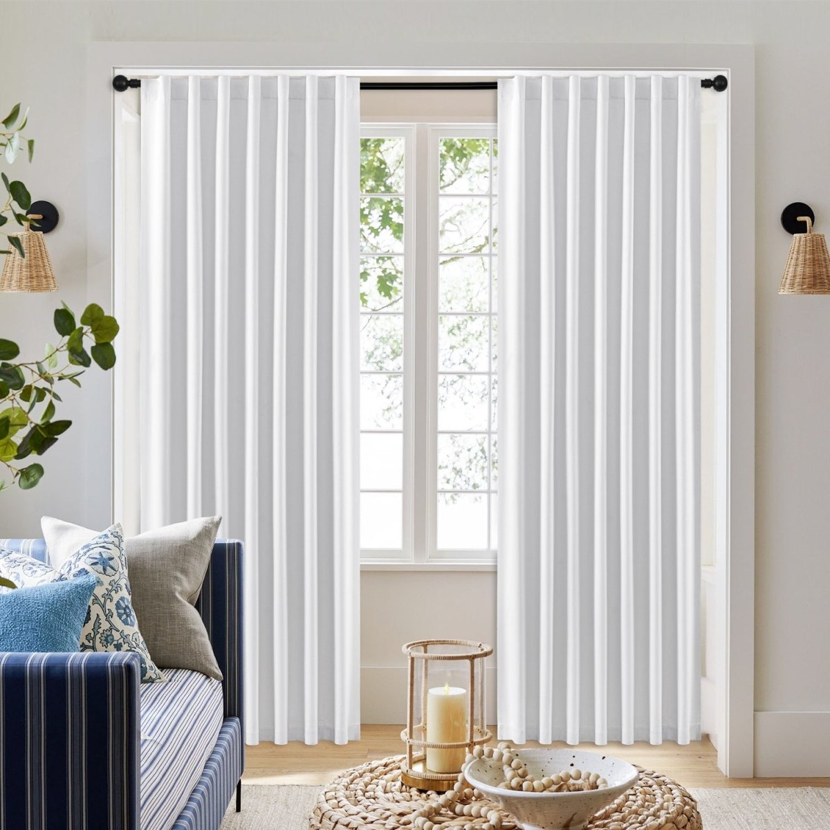 Joydeco white 100% blackout curtains with brushed texture and vertical pleats, shown on a black rod in a living room.