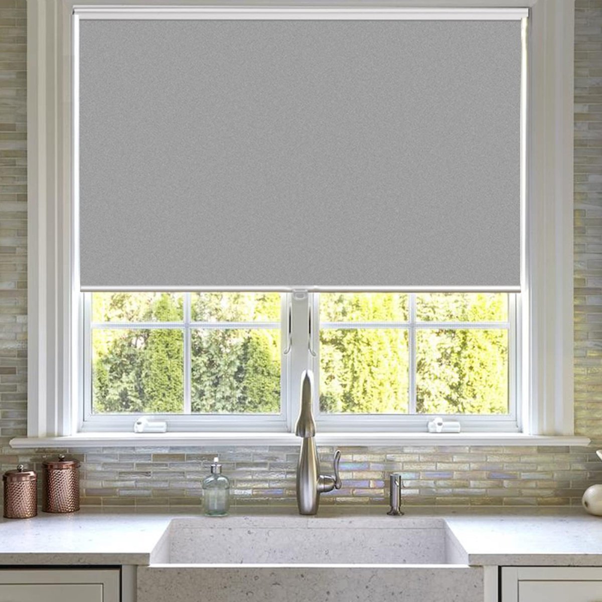 Joydeco light gray cordless blackout roller shade on kitchen window with aluminum bottom rod.