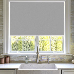 Joydeco light gray cordless blackout roller shade on kitchen window with aluminum bottom rod.