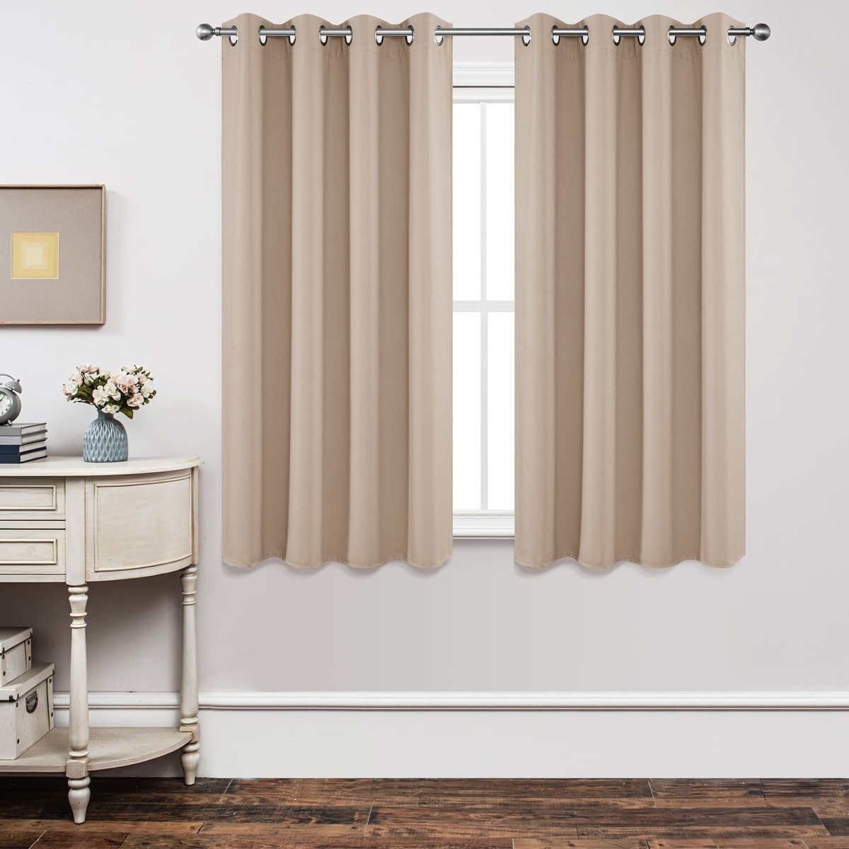 Joydeco beige grommet blackout curtains on silver rod, blocking light from window, near console table.