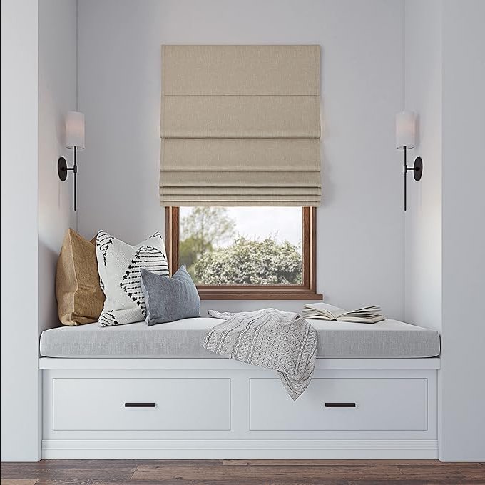 Joydeco beige textured blackout Roman shade, cordless, in window seat area with greenery view.