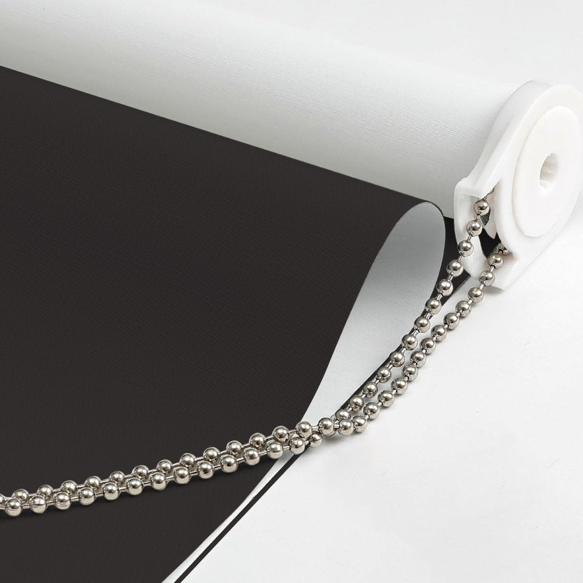 Close-up of black Joydeco blackout roller shade material with beaded pull chain mechanism.
