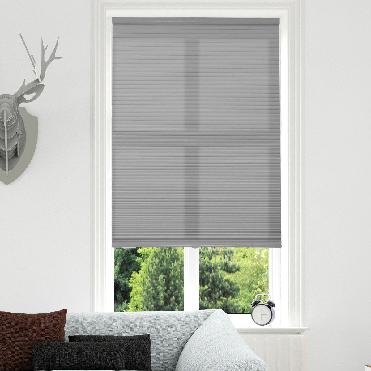 Joydeco custom light grey cordless motorized cellular shade, filtering light from outside trees.