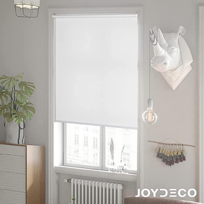 Joydeco white 100% blackout roller shade installed in a modern room with urban window view, potted plant, and rhino decor.