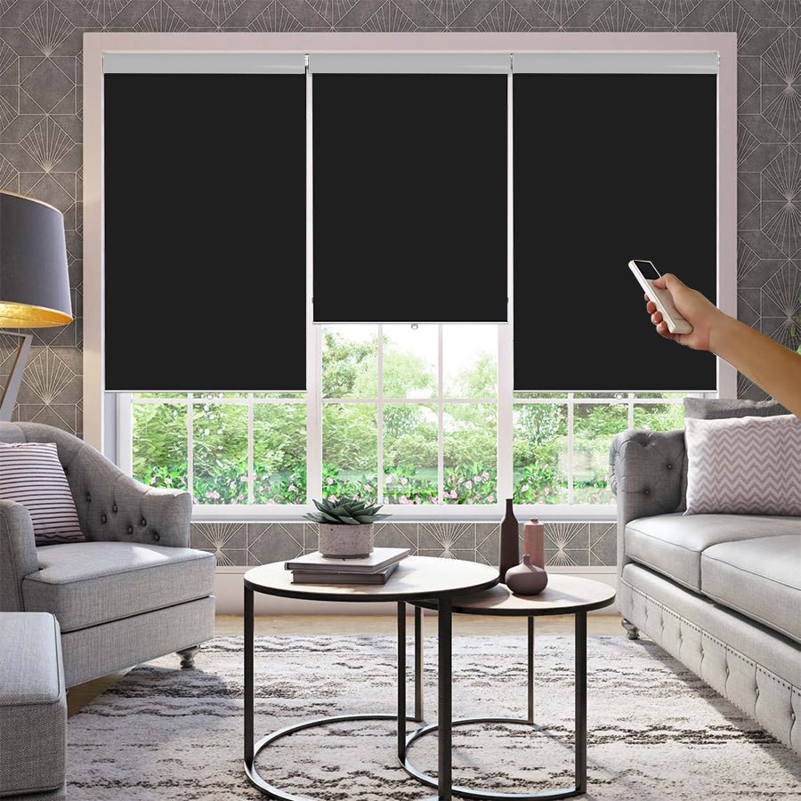 Black Joydeco motorized blackout roller shades controlled by remote in a modern living room.
