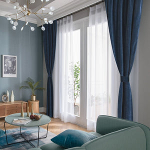 Custom deep navy blue velvet blackout curtains layered with sheer white, enhancing room ambiance.