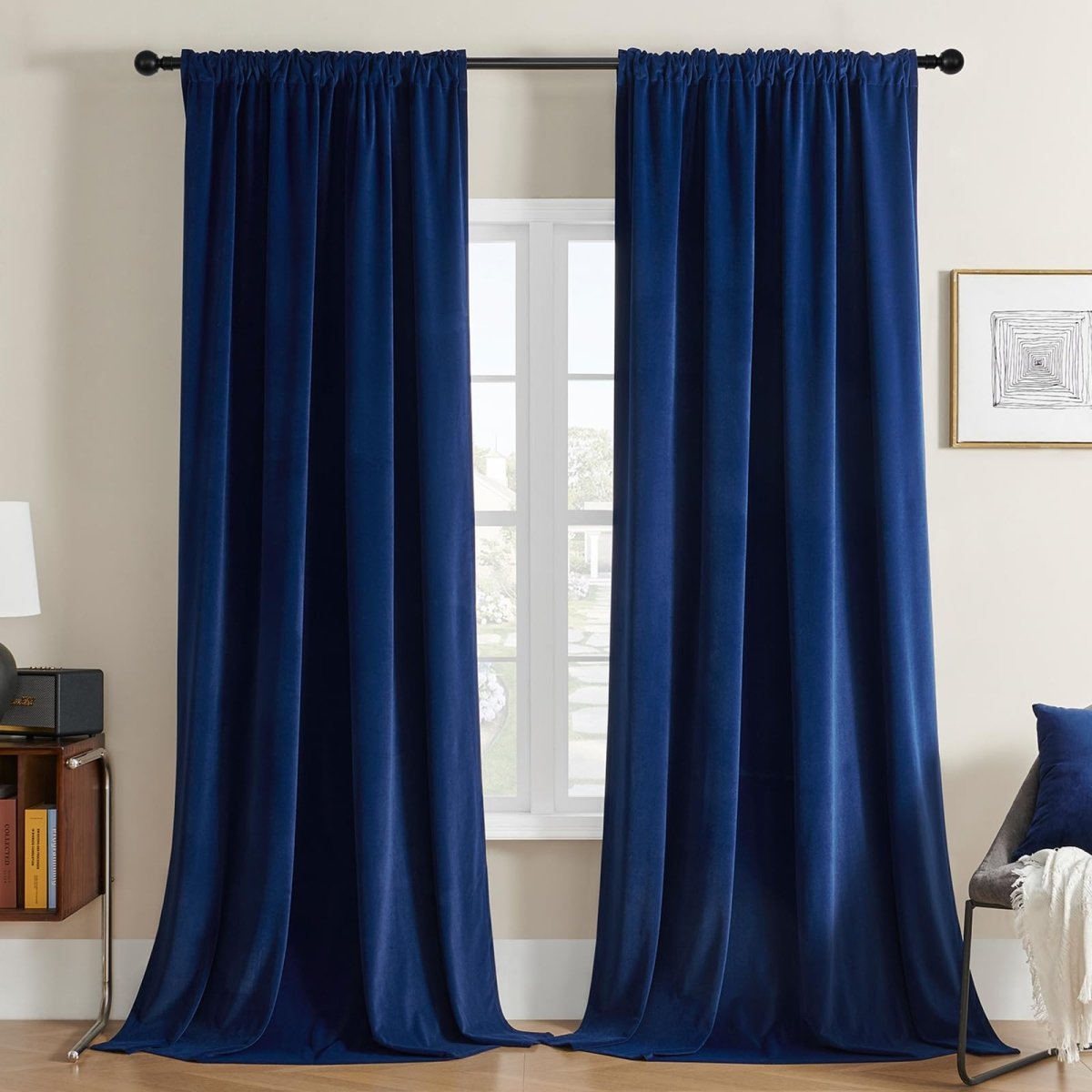 Two royal blue velvet blackout curtains with rod pocket design hanging.
