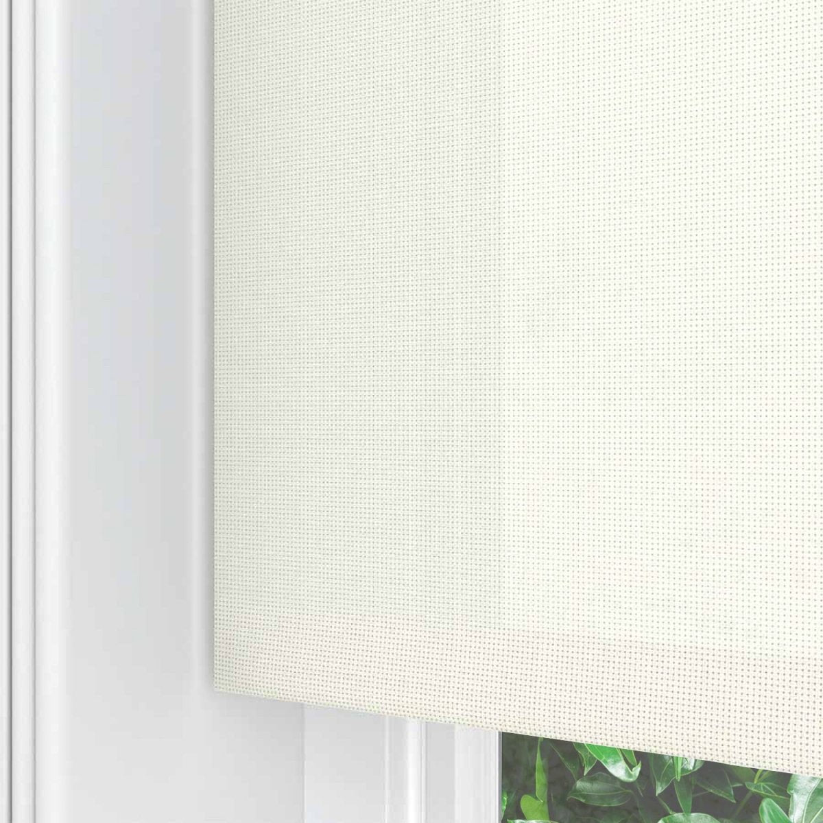 Cream Joydeco blackout solar shade with fine dot texture, white window frame, and outdoor view.