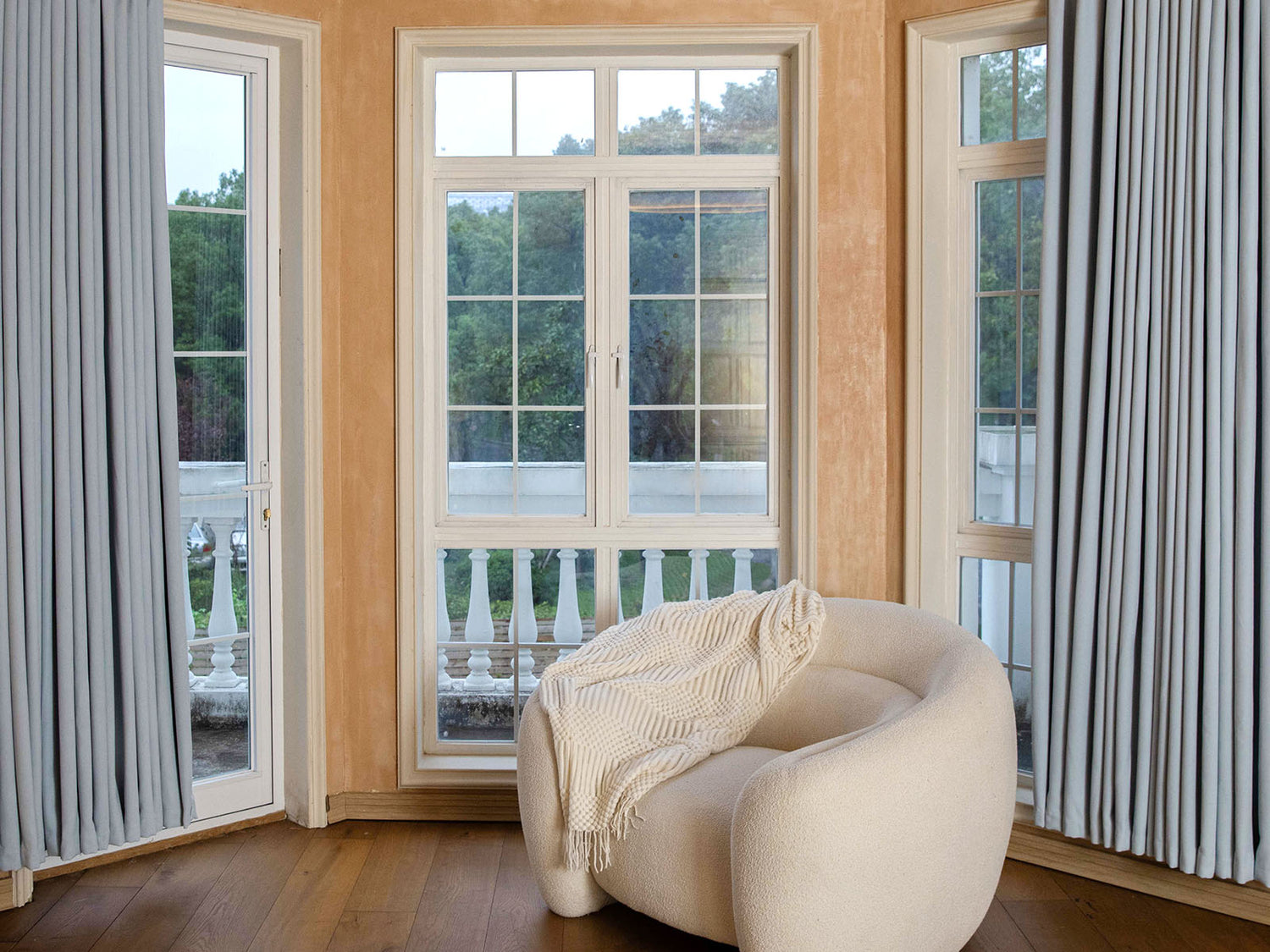 Joydeco light gray blackout curtains in a cozy room with a white bouclé chair.