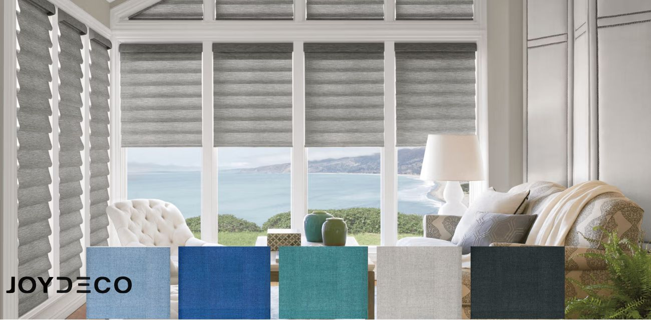 JOYDECO custom Roman shades in various colors like grey and blue, shown on large windows with a sea view