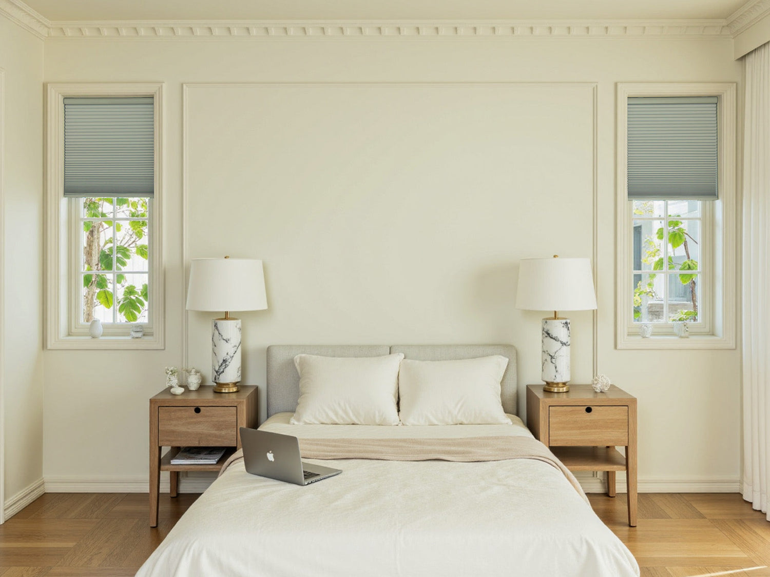 Minimalist bedroom with gray cellular shades and marble bedside lamps.