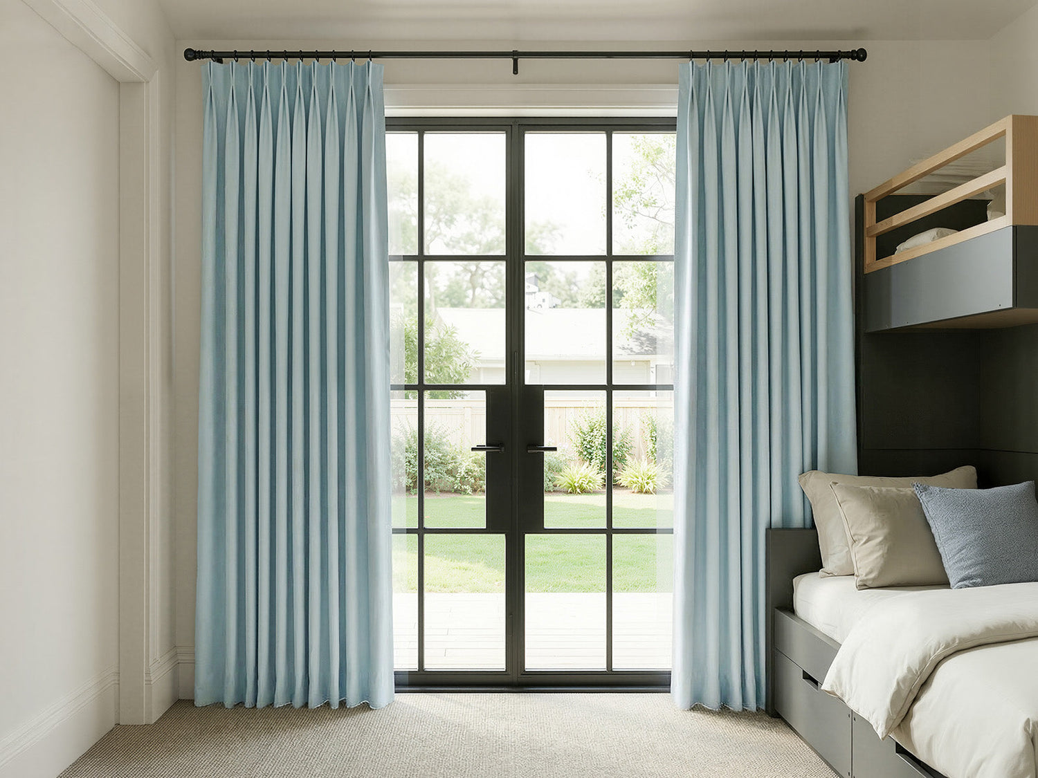 Joydeco blue pleated curtains on black rod framing large glass doors in a modern bedroom.