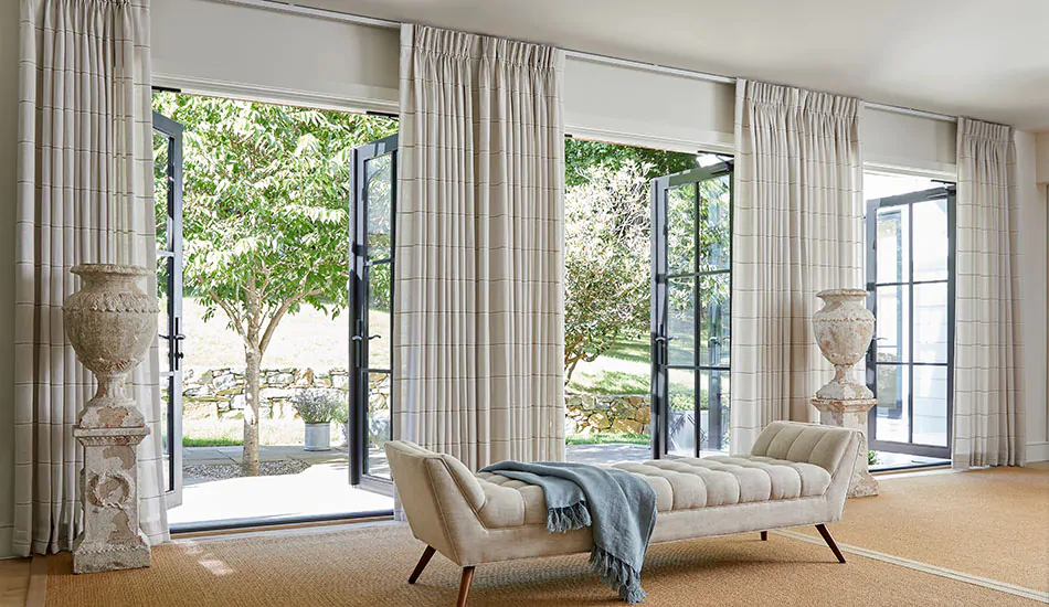 Light patterned curtains framing glass doors to a garden, with a tufted bench.