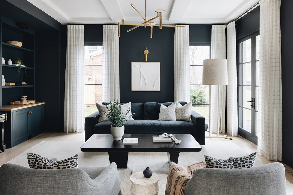 Elegant living room with dark walls and sheer, patterned curtains on large windows.