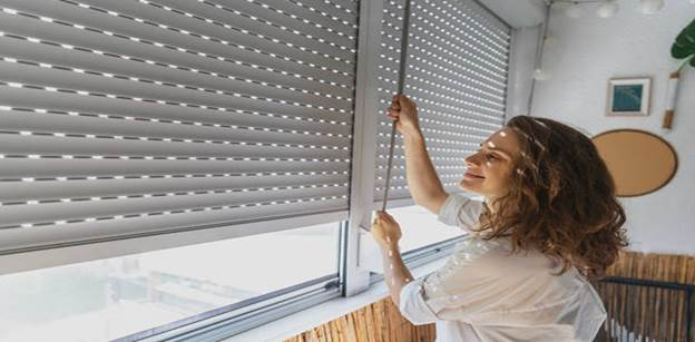 A person adjusting modern roller shutters in a bright, well-lit room.