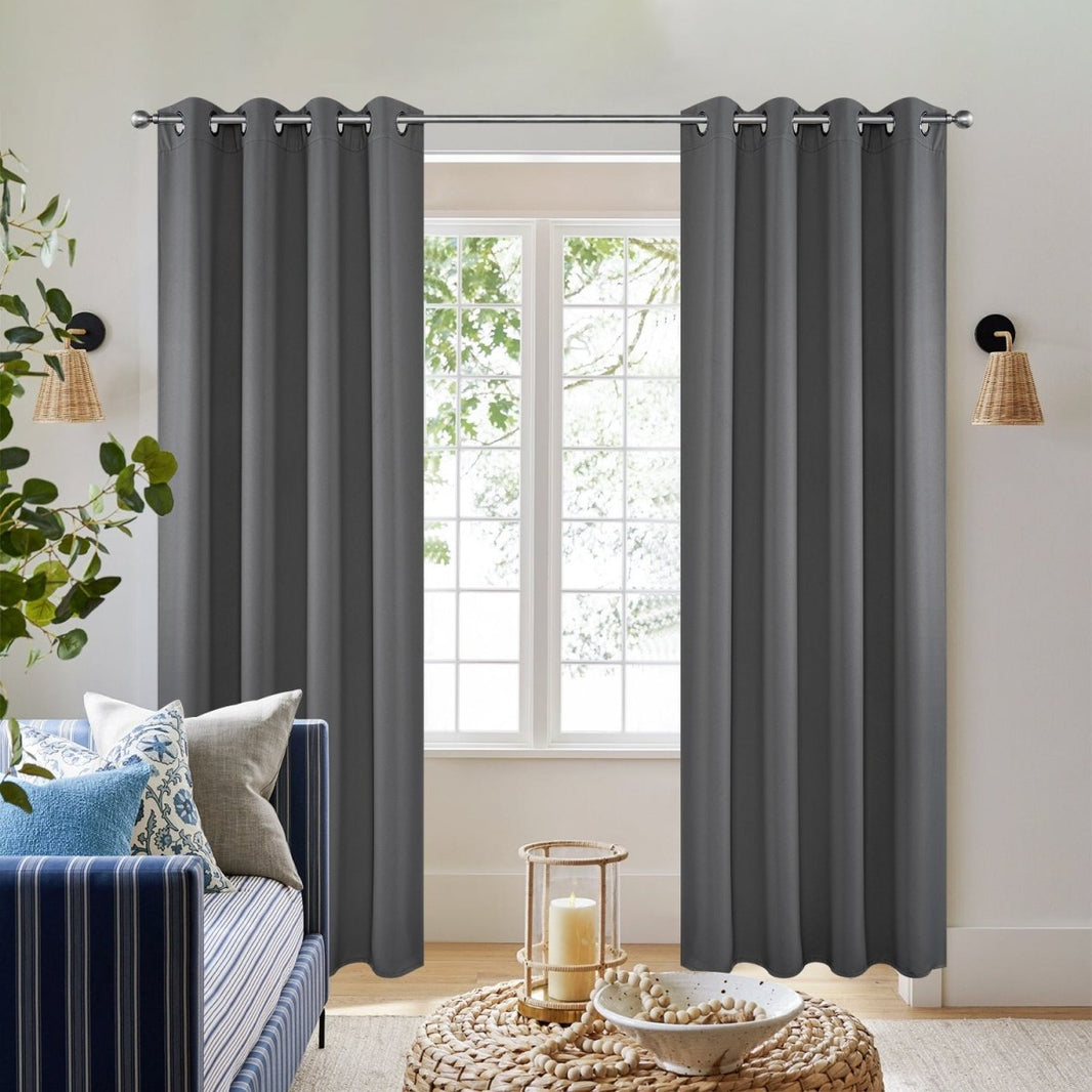 Dark grey polyester blackout curtains with grommet tops shown on rod in a living room setting.