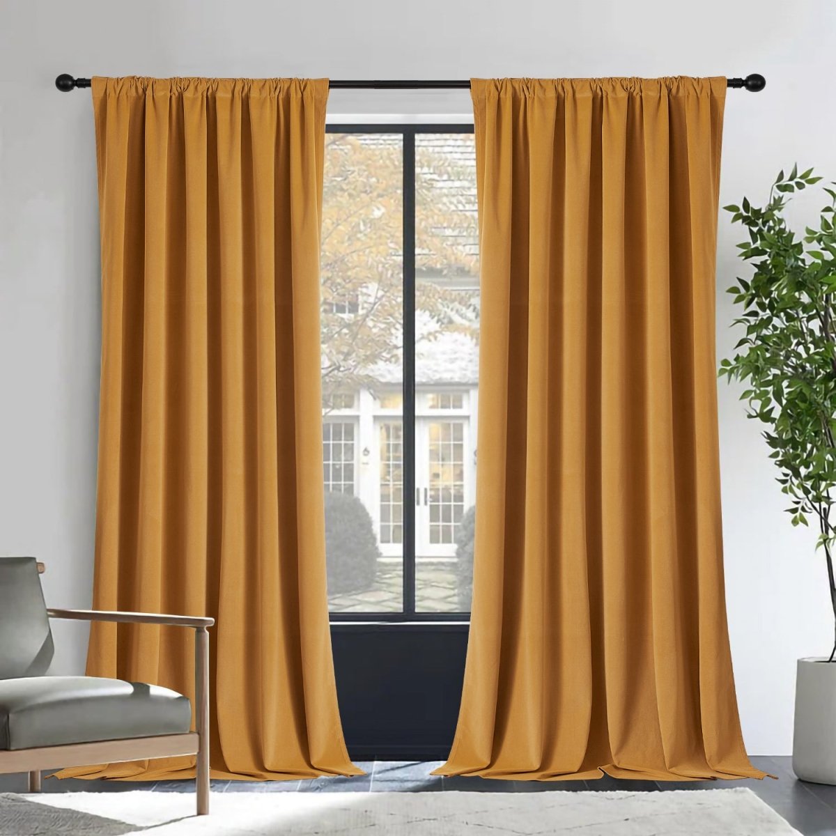 Two mustard-yellow Joydeco velvet blackout curtains on black rod, room with grey armchair and plant.