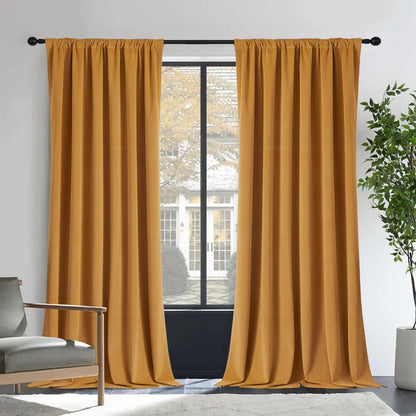Two mustard-yellow Joydeco velvet blackout curtains on black rod, room with grey armchair and plant.