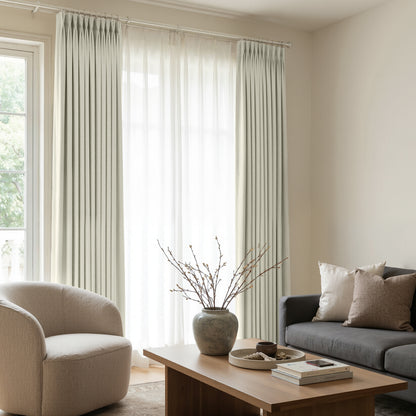 Custom Arden Satin Blackout Curtain in light neutral color, elegantly pleated and layered with sheer curtains for home decor.