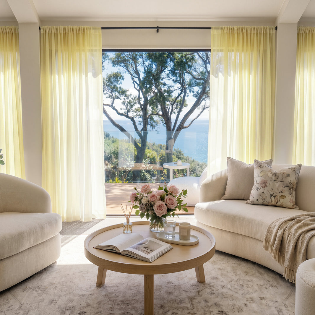 Joydeco custom sheer curtains in pale yellow, framing a serene ocean view in an airy living room.