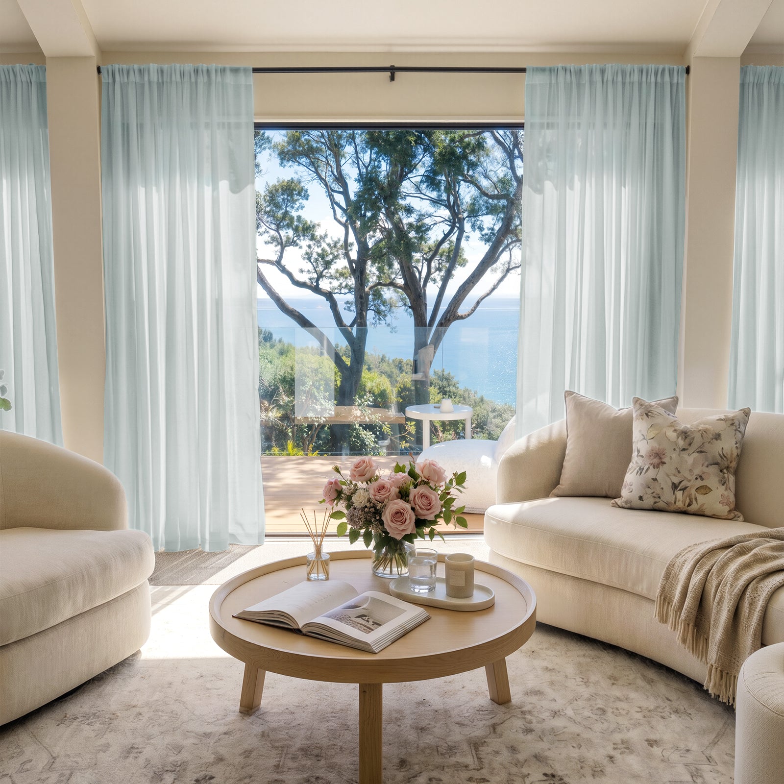 Light blue custom sheer curtains softly filter sunlight in a living room with ocean view.