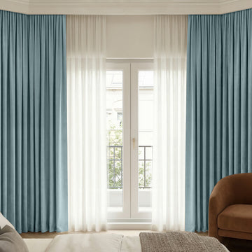 Bennett Chenille blackout curtains in blue, layered with sheer white curtains on a French door.