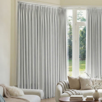 Custom light grey Mason triple weave blackout curtains in a living room.