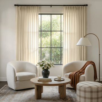 Custom light beige sheer curtains with geometric jacquard texture and pom trim.