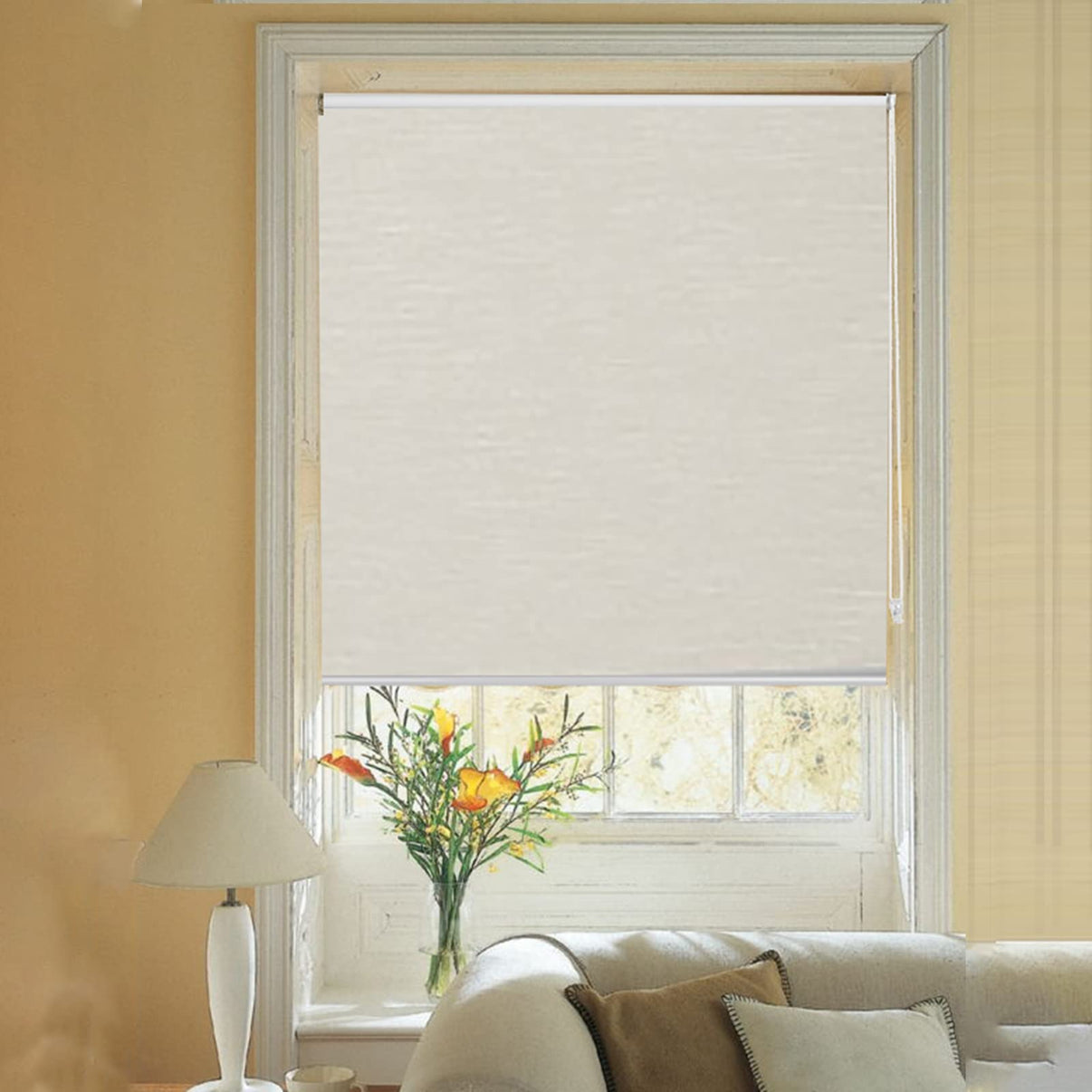 Cream striped jacquard cordless blackout roller shade partially lowered in a living room with floral arrangement.