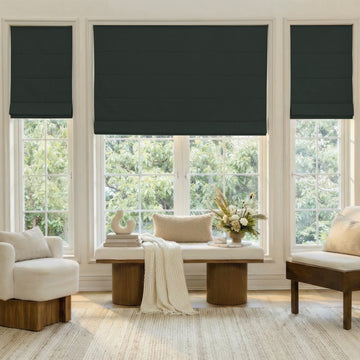 Alder Faux Linen Blackout Roman Shade in dark green installed in a stylish room.