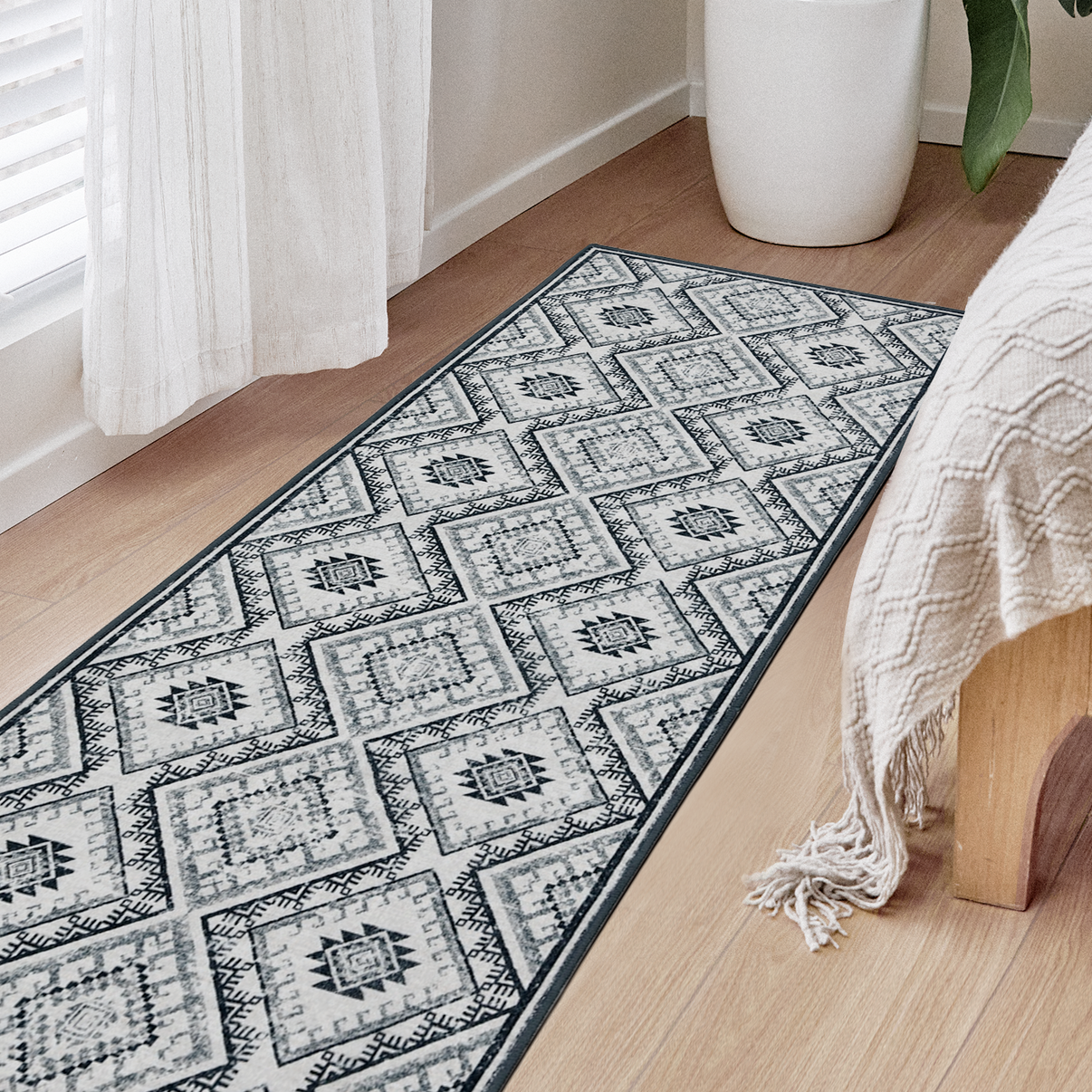 Joydeco vintage geometric runner rug in grey and white, laid on light wood floor beside a bed in bedroom.