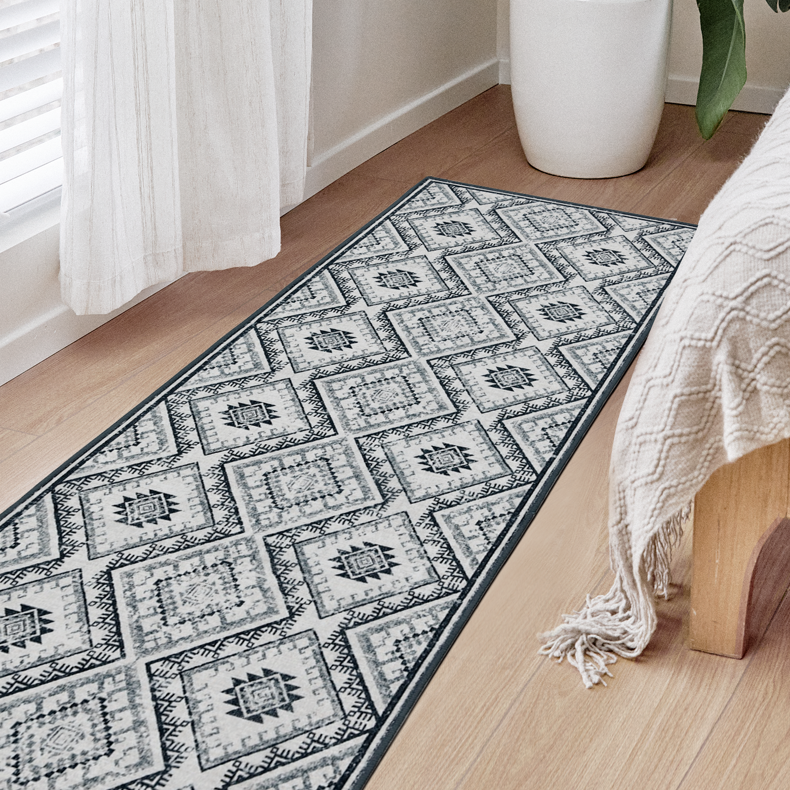 Joydeco vintage geometric runner rug in grey and white, laid on light wood floor beside a bed in bedroom.