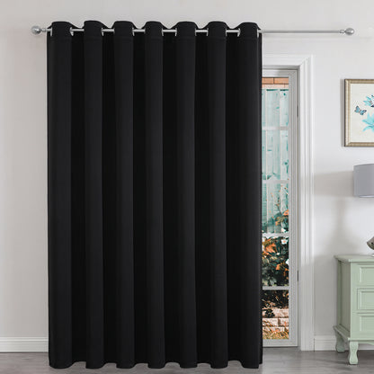 Black extra-wide blackout curtain panel for sliding glass door in a living room, providing privacy and light control.