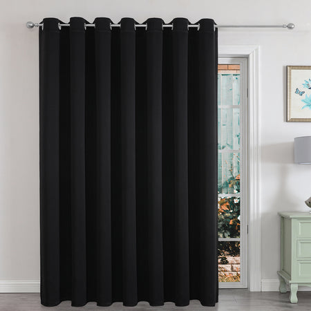 Black extra-wide blackout curtain panel for sliding glass door in a living room, providing privacy and light control.