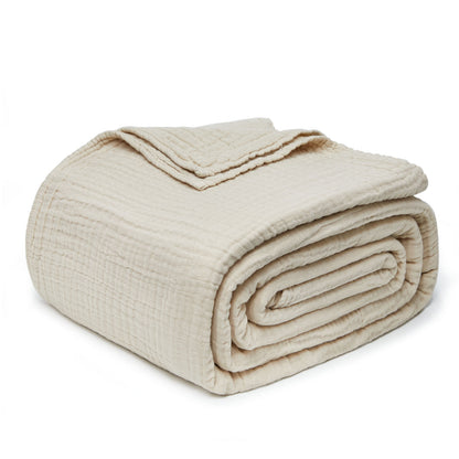 Rolled light beige 4-layer cotton muslin throw blanket with visible gauze texture and stitching, perfect for all seasons.