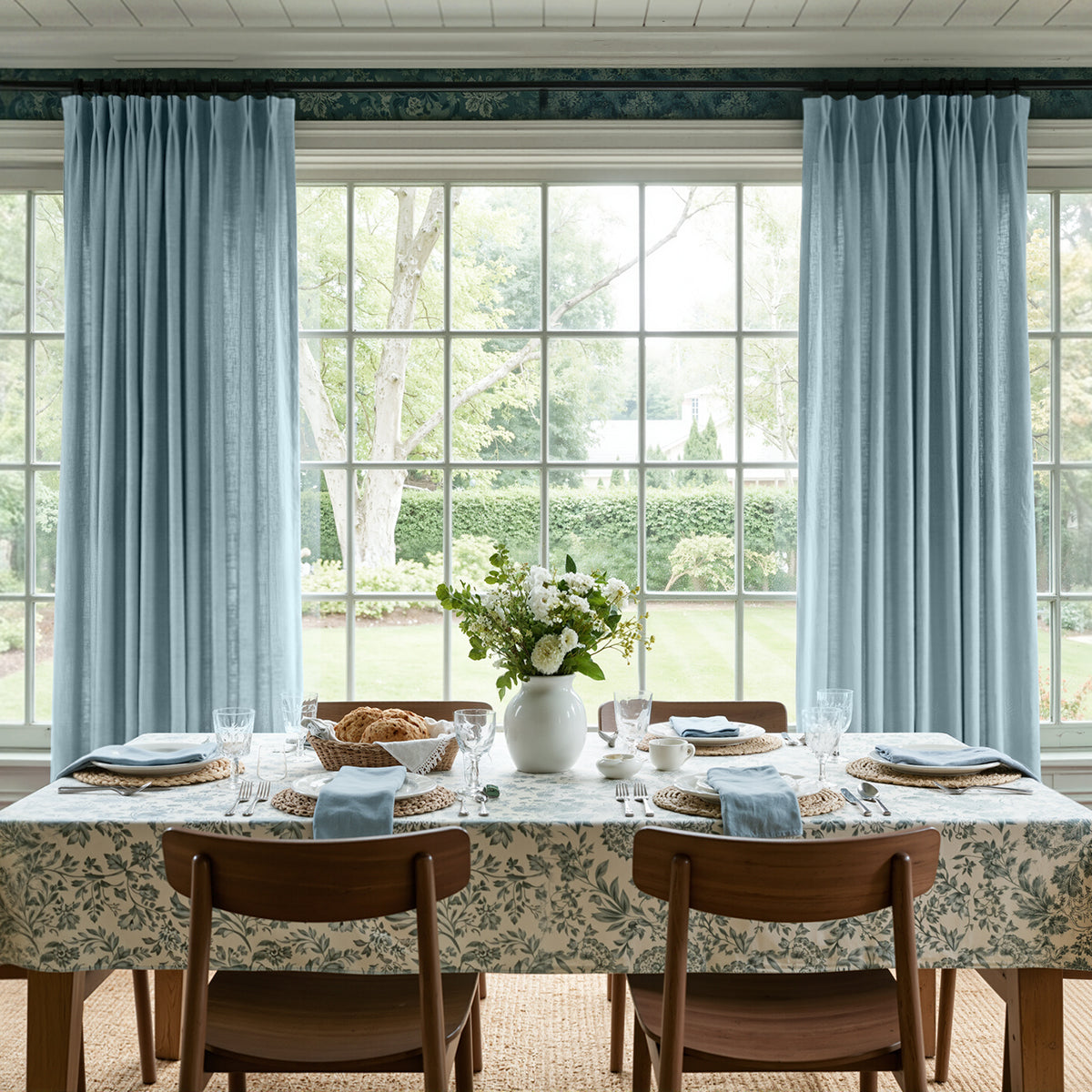 Light blue textured curtain panels framing a bright dining room window