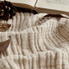 Close up of beige 4-layer cotton muslin throw blanket with gauze texture, natural aesthetic.
