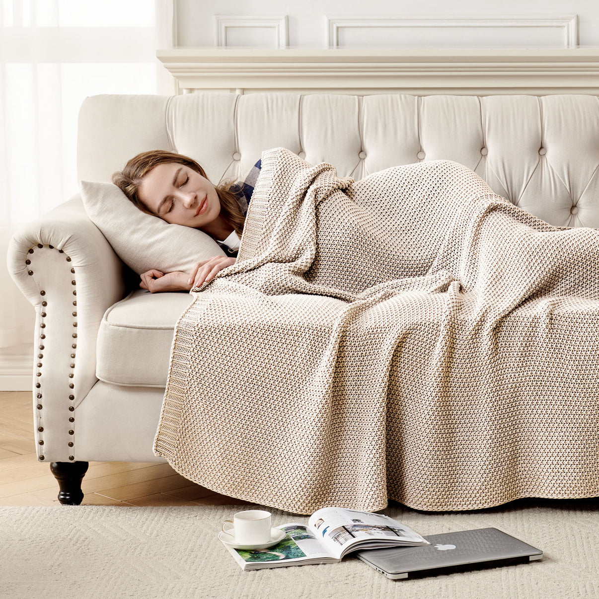 Woman sleeping on couch under light beige 100% cotton cable knit throw blanket, emphasizing coziness and home decor.