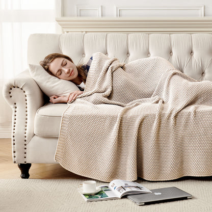 Woman sleeping on couch under light beige 100% cotton cable knit throw blanket, emphasizing coziness and home decor.