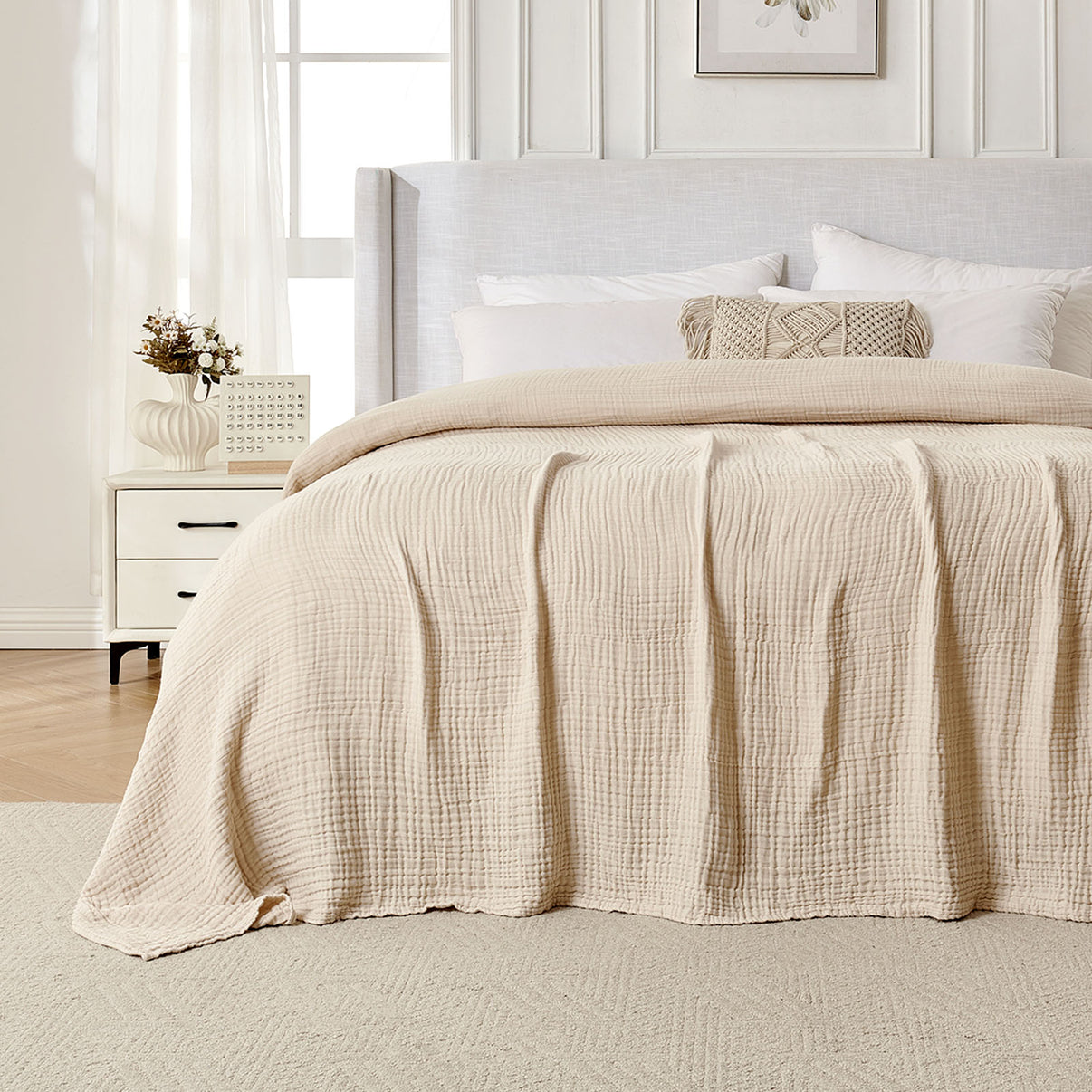 Beige 4-layer cotton muslin throw blanket with gauze texture on a bed.