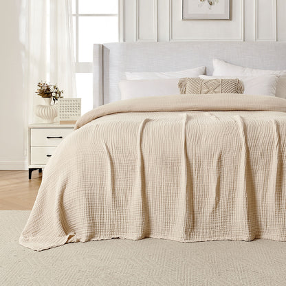 Beige 4-layer cotton muslin throw blanket with gauze texture on a bed.