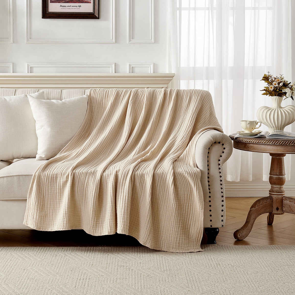 Beige 4-layer cotton muslin throw blanket with gauze texture draped on a sofa.