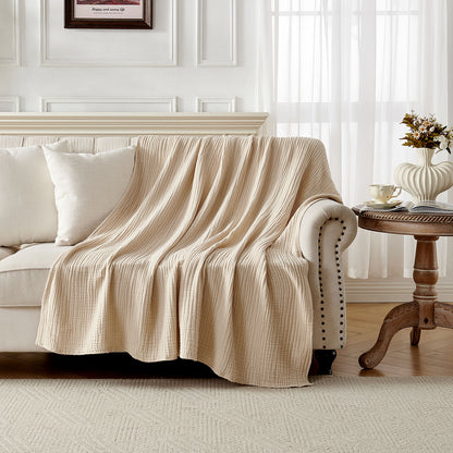 Beige 4-layer cotton muslin throw blanket with gauze texture draped on a sofa.