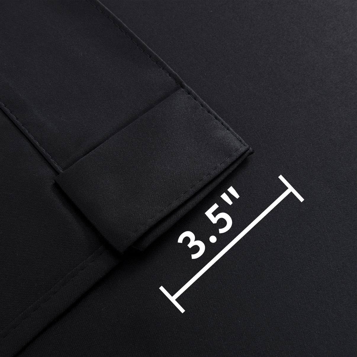 Close-up of Joydeco black blackout curtain fabric showing 3.5-inch back tab for hanging options.