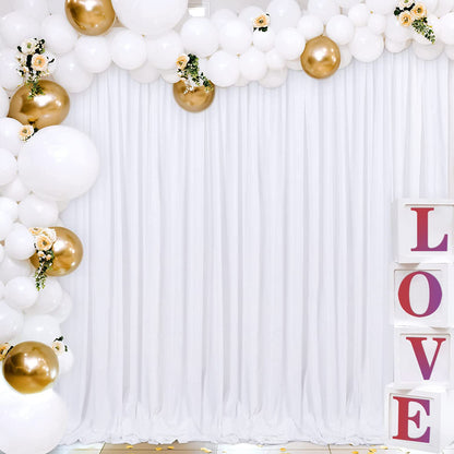 White polyester backdrop curtain with white and gold balloon arch and 'LOVE' blocks for party decor.