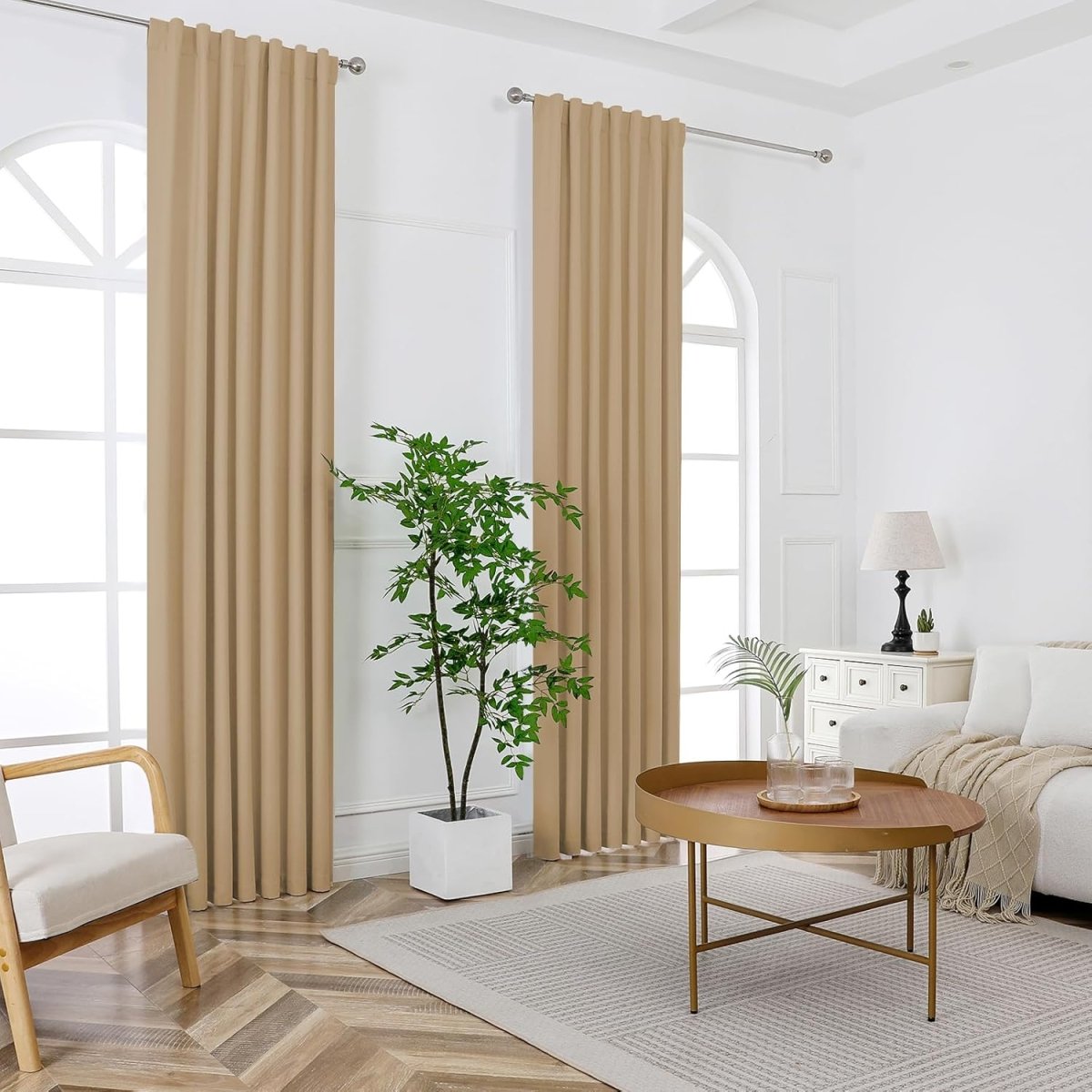 Two dark beige Joydeco thermal blackout curtains with sanded fabric hang from a rod, framing arched windows in a living room.